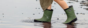 Girl walking on a big puddle wearing the cypress natural rubber rain boots