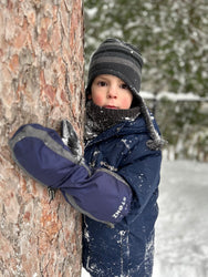 Cute Kid in Stonz Snow mitts in Navy/heather grey holding a tree.