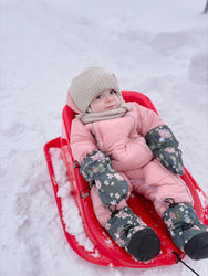 Cute baby in stonz baby mitts and booties in the snow.