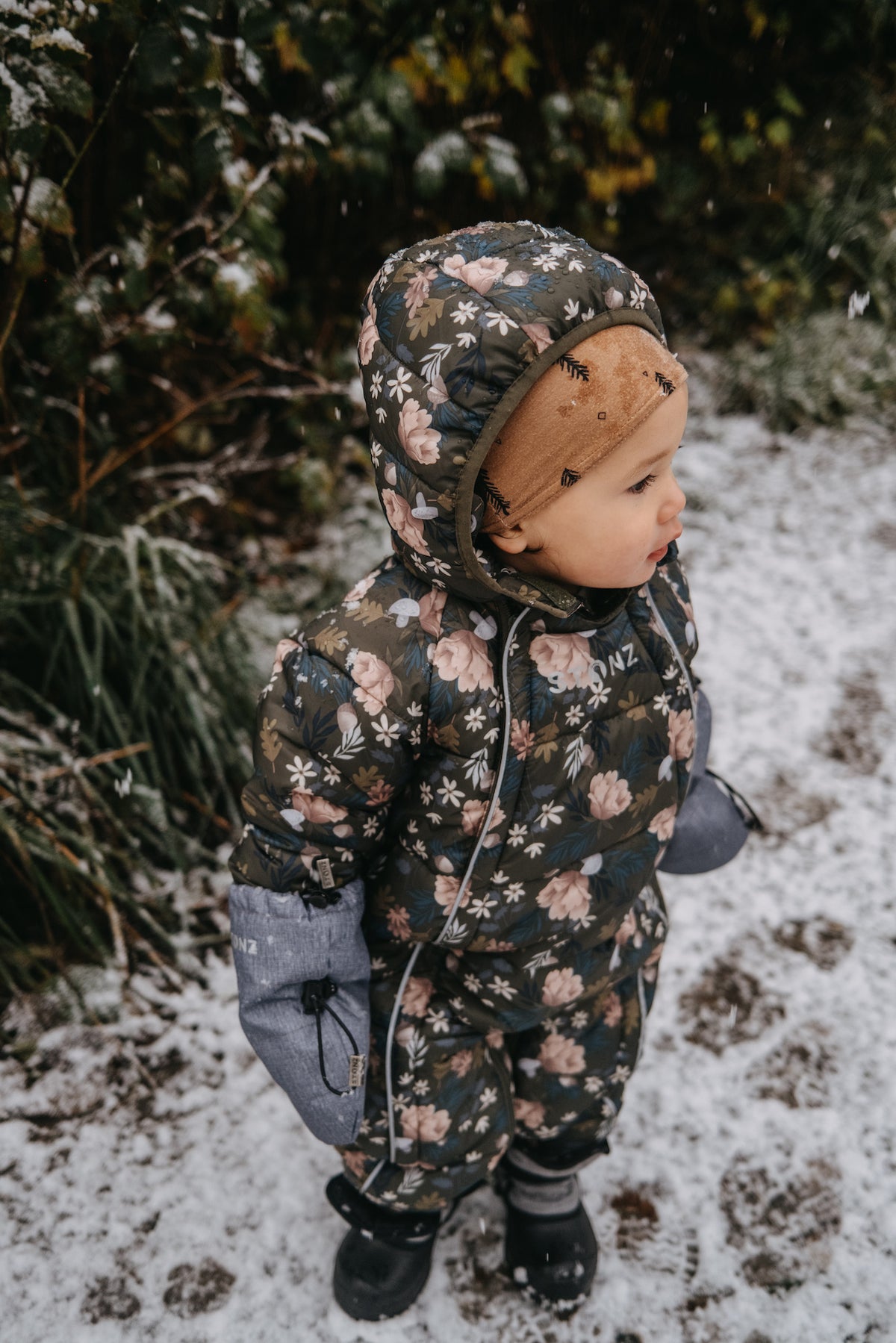 A cute baby wearing stonz woodland snow suit in the snow alt::Woodland