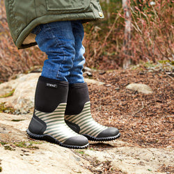 Stonz West Boot in Cypress/Sage, shown close up on a child standing outdoors.