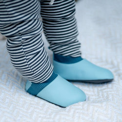 Stonz Yale baby shoe in Haze Blue - Denim, shown up close on an infant standing on a blanket.