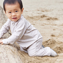Stonz Yale baby shoe in Dune - Ivory, shown on an infant crawling in the sand.