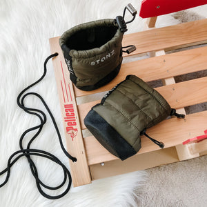 Stonz Puffer Baby Booties in Pine, laying on a wooden sled.