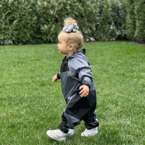 Stonz Rain Suit in Heather Grey on an infant walking outside on the grass.
