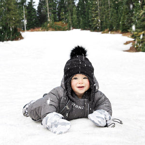 Stonz Snow Suit in Heather Grey, worn by an infant laying outside in the snow.